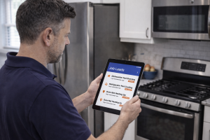 Appliance repair technician checking a tablet for high intent job leads inside a modern kitchen.